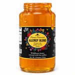 Honey Feast Allergy Blend Honey in an open 3lb glass jar, with honey dripping over the rim, on a white background.