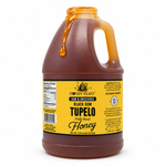 Honey Feast Black Gum Tupelo 6lb bulk honey in a frosted HDPE plastic jug with the handle on the right, with honey dripping over the open rim on a white background.