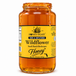 Honey Feast Wildflower Honey in an open 3lb glass jar, with honey dripping over the rim, on a white background.