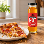Hot Honey glass jar beside a pepperoni pizza slice with a honey drizzle