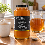 Honey Feast Manuka Infused Honey with Propolis – 3lb Glass Jar beside a tea pitcher and two mugs
