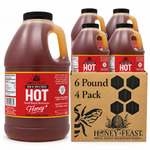 Honey Feast Hot honey 4-pack of 6lb frosted HDPE plastic jugs with wide black screw caps, shown with the branded shipping carton on a white background.