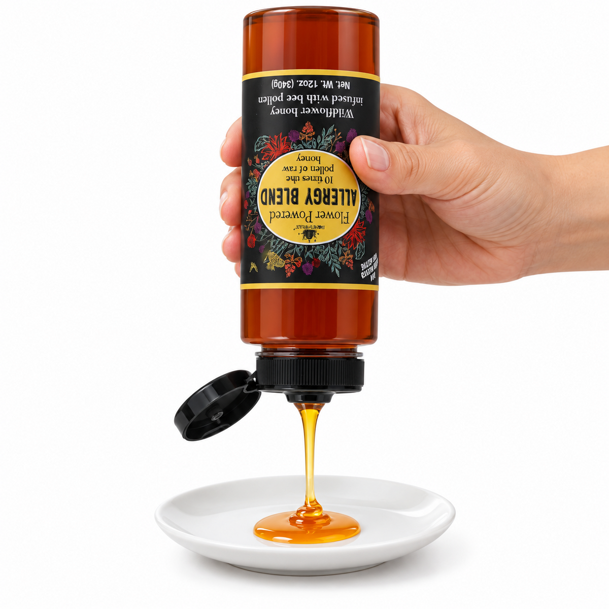 Hand squeezing an inverted Honey Feast Allergy Blend 12oz plastic bottle onto a small white plate, with the label upside down and the flip-top cap open