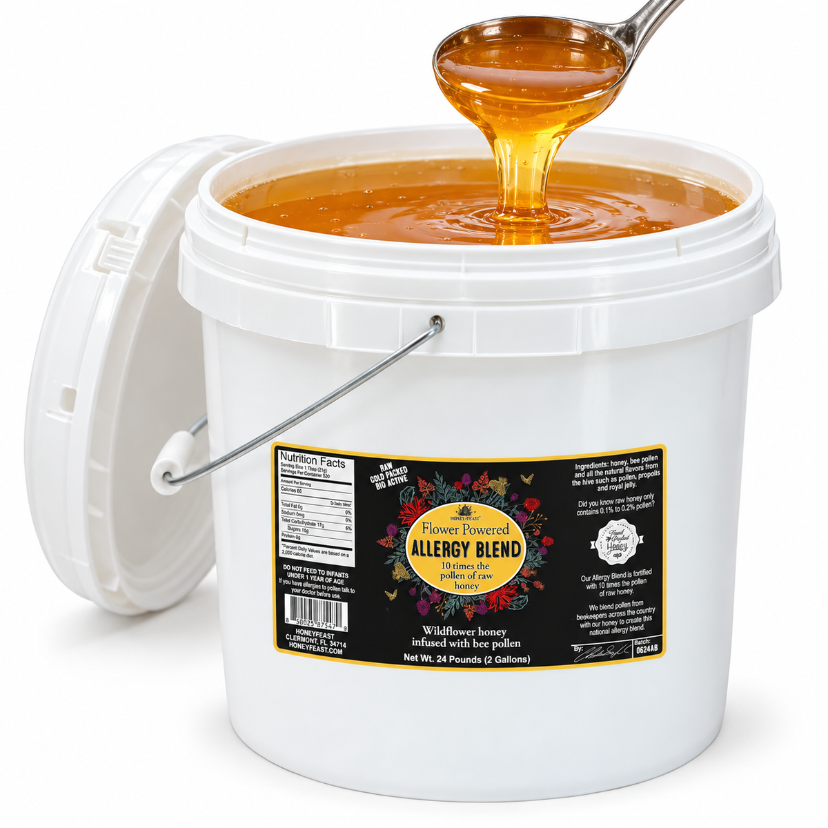 Open Honey Feast Allergy Blend Honey 2-gallon bucket with golden honey flowing from a stainless steel ladle, on a white background.