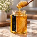Open Honey and Honeycomb jar with honey dripping from a spoon