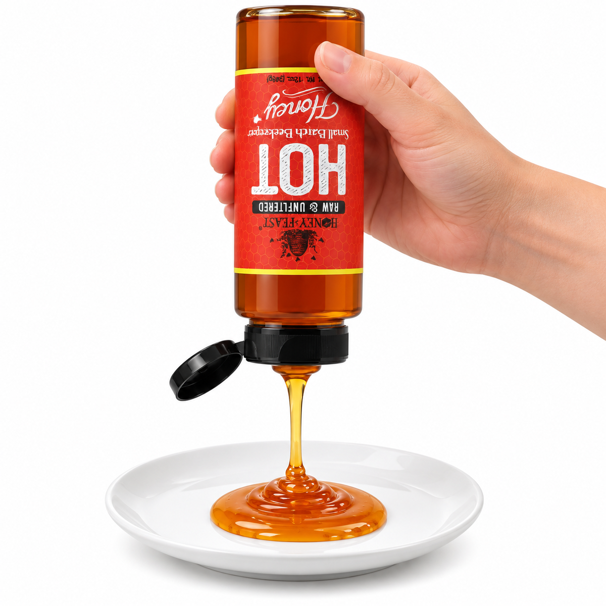 Hand squeezing an inverted Honey Feast Hot Honey 12oz plastic bottle onto a white plate with the flip-top lid open and label correctly upside down