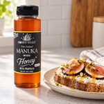 Honey Feast Manuka Infused Honey with Propolis 12oz plastic squeeze bottle beside fig and ricotta toast with a drizzle of honey