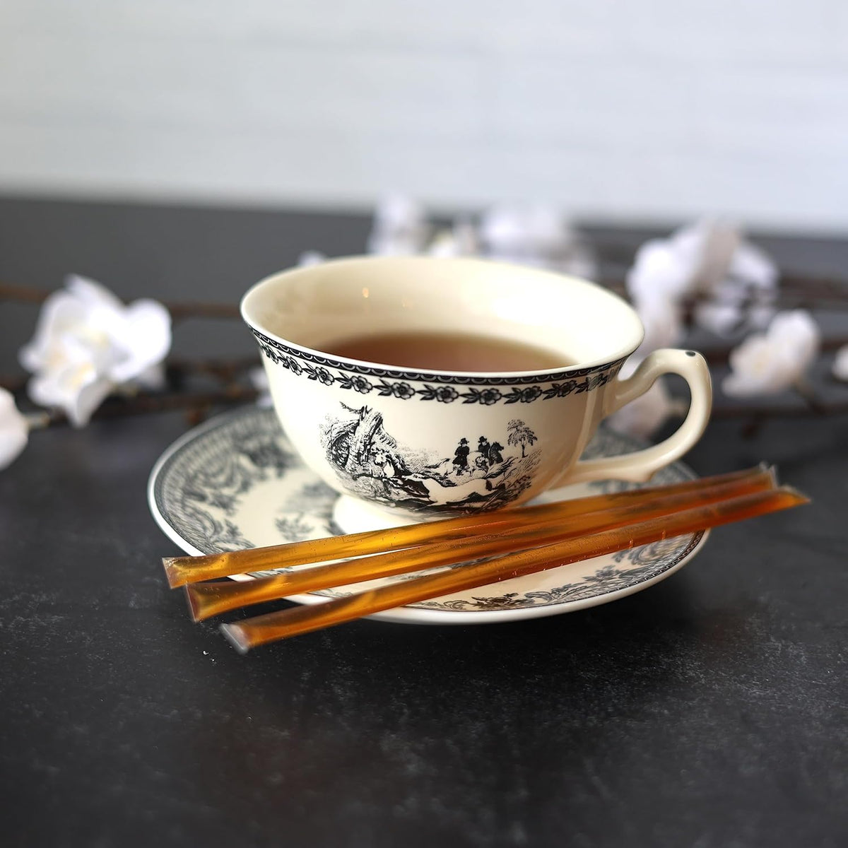 Manuka and propolis honey sticks served beside a cup of tea