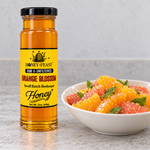 Honey Feast Raw Orange Blossom Honey 12oz glass jar beside a citrus salad