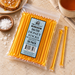 Salted Honey Sticks 50-pack lying flat beside sea salt, toast and tea with full-length loose sticks