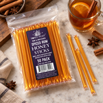 Honey Feast Spiced Rum Honey Sticks 50-pack lying beside a warm drink with orange, cinnamon and star anise