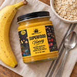Overhead view of Honey Feast Superfood Honey 12oz glass jar with a banana, oats and a spoon