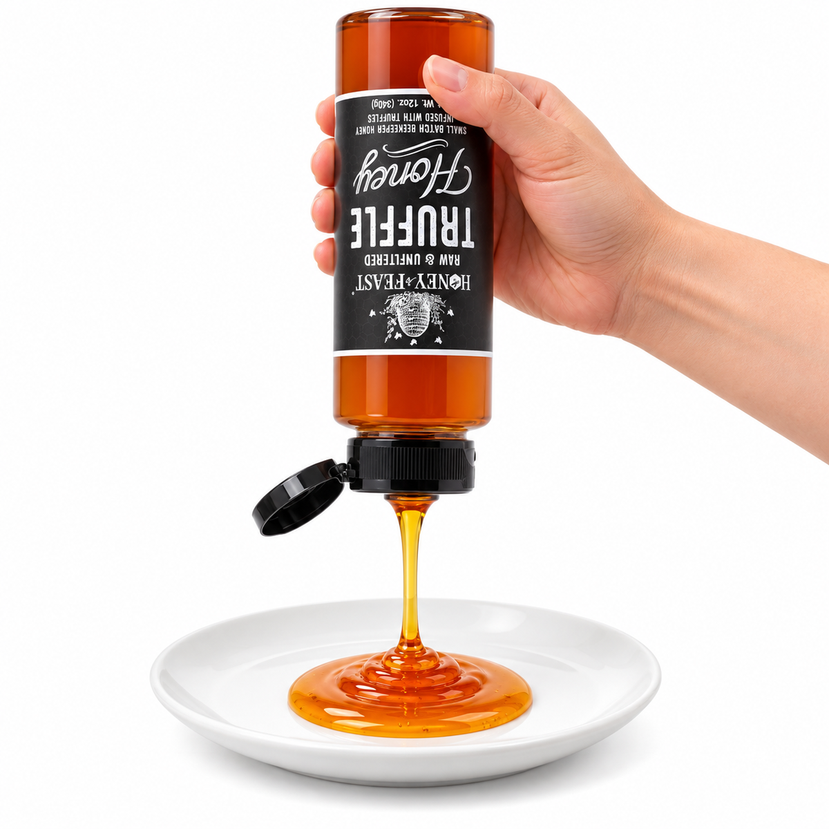 Hand squeezing an inverted Truffle Honey 12oz plastic bottle onto a white plate with the flip-top lid open and label correctly upside down