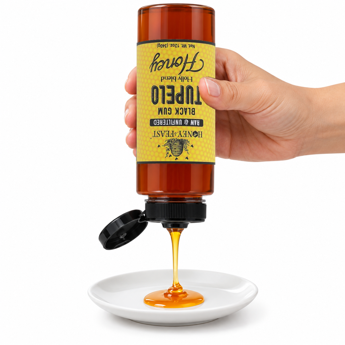 Hand squeezing Honey Feast Black Gum Tupelo Honey from an inverted 12oz plastic bottle onto a small white plate; bottle label is upside down