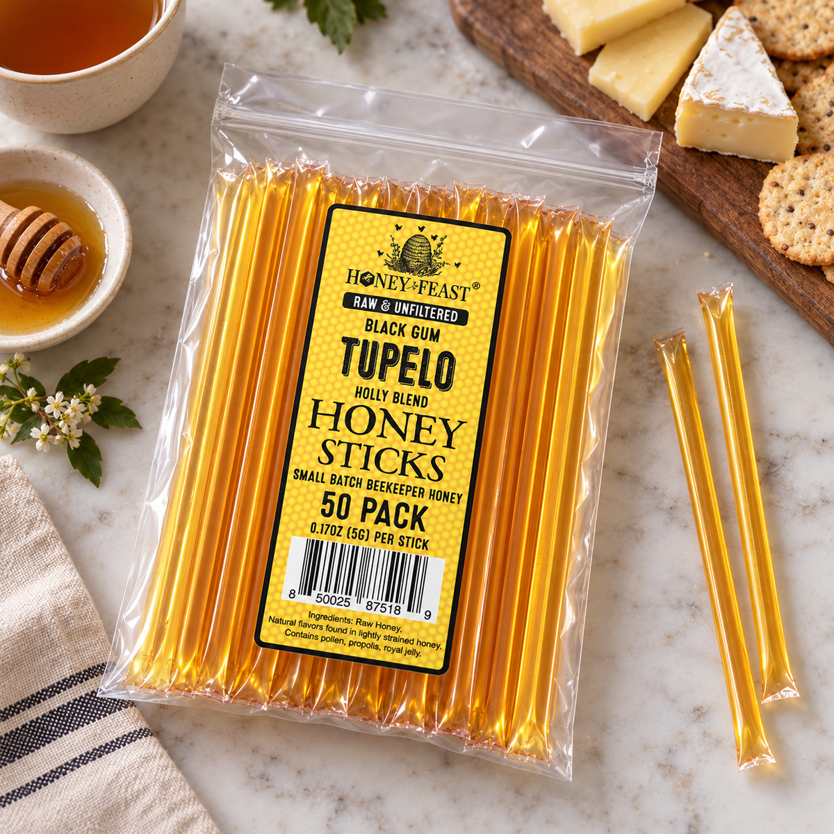 Black Gum Tupelo Honey Sticks 50-pack lying flat beside a simple cheese and tea setting, with full-length loose sticks