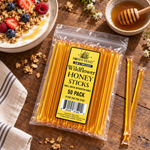 Wildflower Honey Sticks 50-pack lying flat beside yogurt and berries, with full-length loose sticks